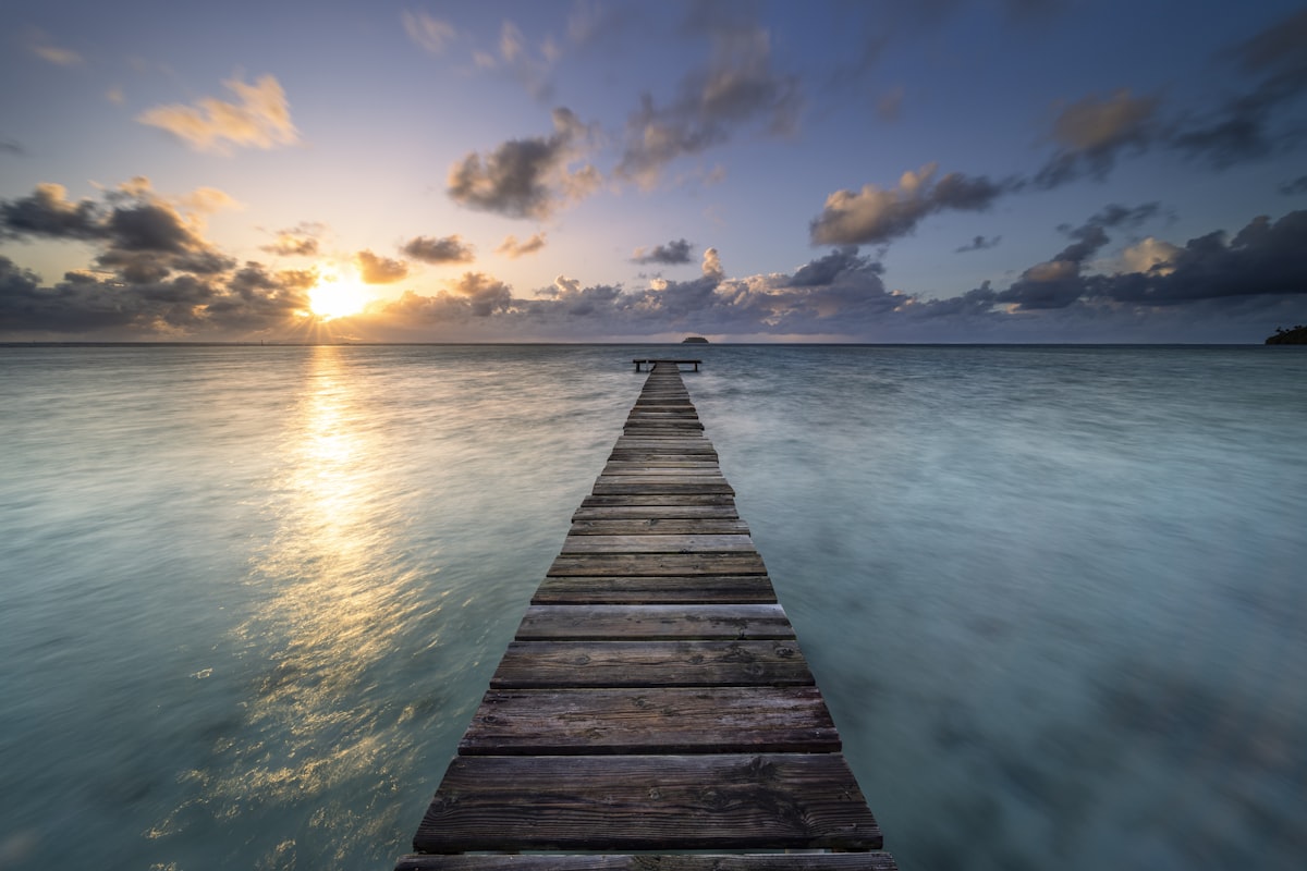 Wooden pier extending into the ocean at sunset