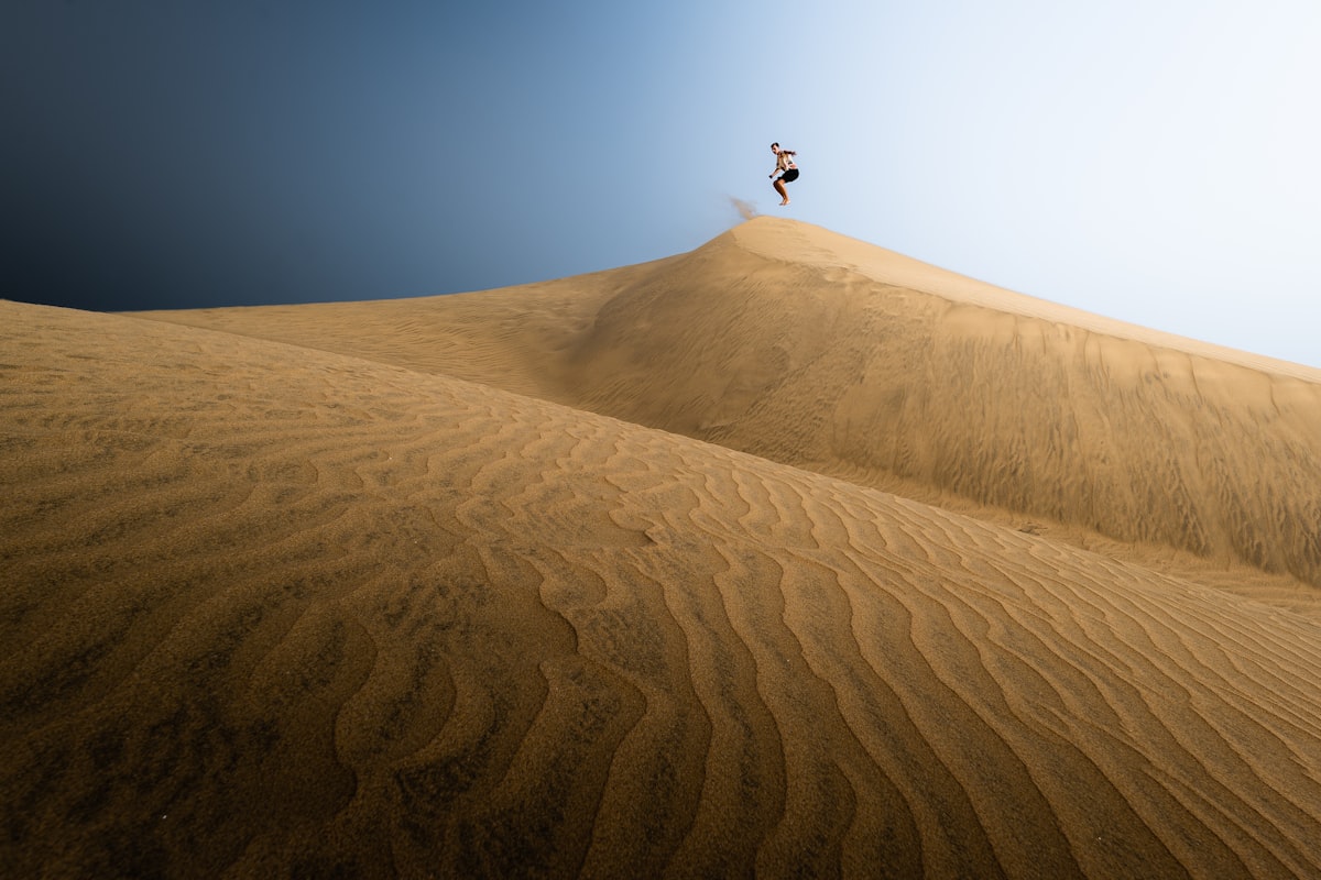 Sandboarding down a white sand dune